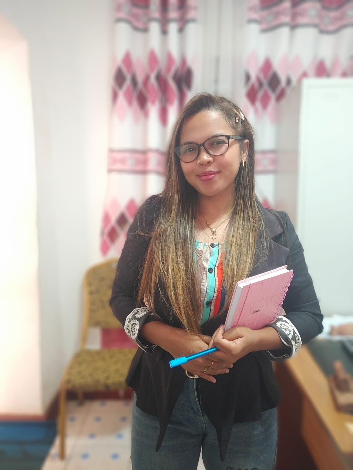 Fleurette debout dans son bureau, un carnet rose et un stylo à la main